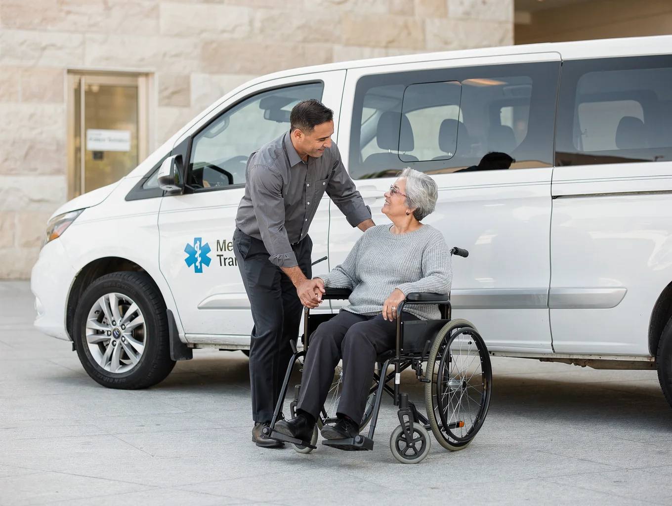 Caregiver driver assisting passenger with wheelchair into accessible medical transport vehicle